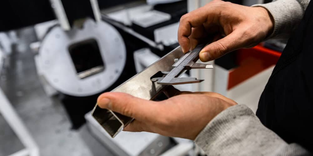 Mitarbeiter misst Metall mit Präzisionswerkzeug in der Werkstatt.